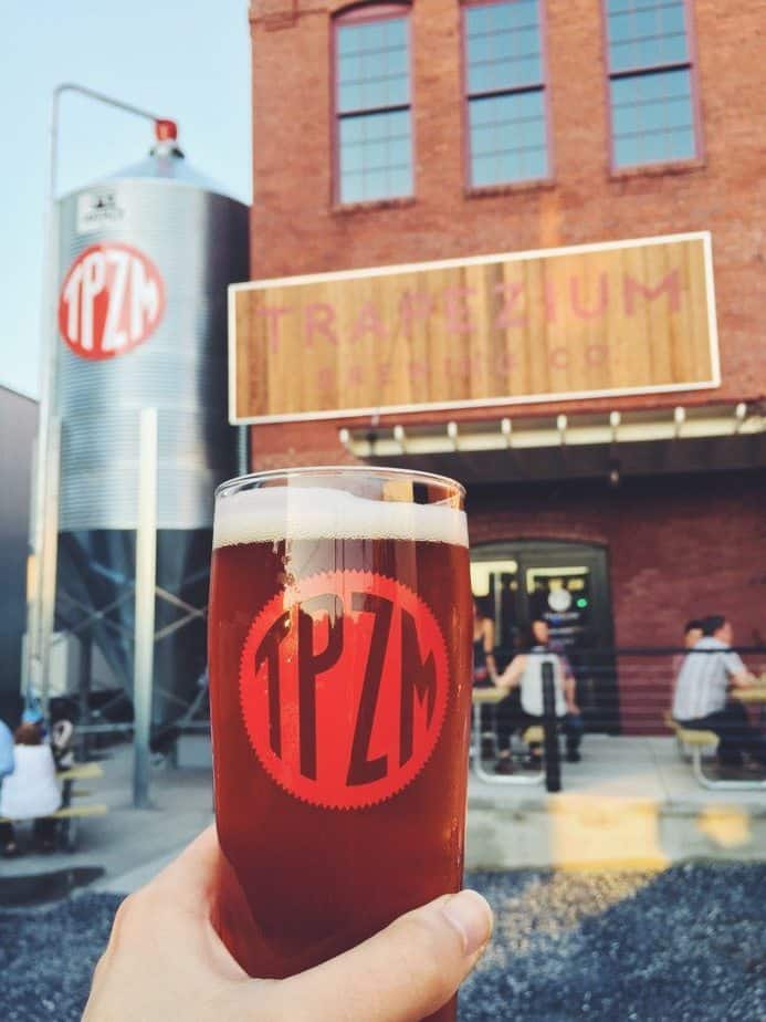 glass of beer in foreground, brewery in background