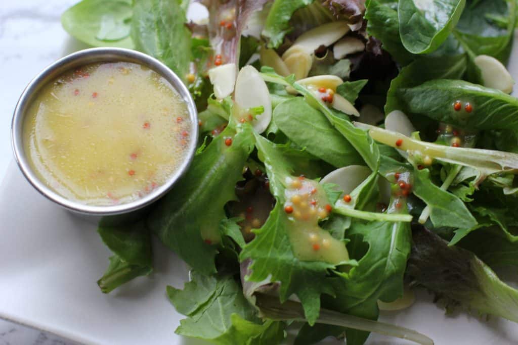 Honey Mustard Dressing in a cup next to salad