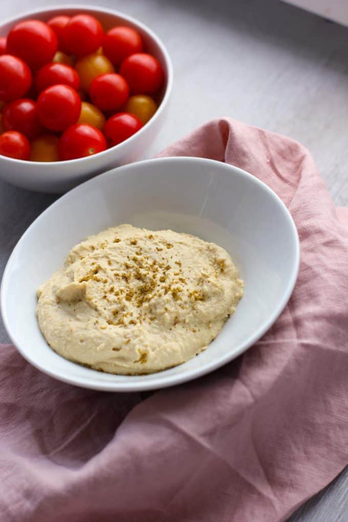 hummus in a dish next to tomatoes