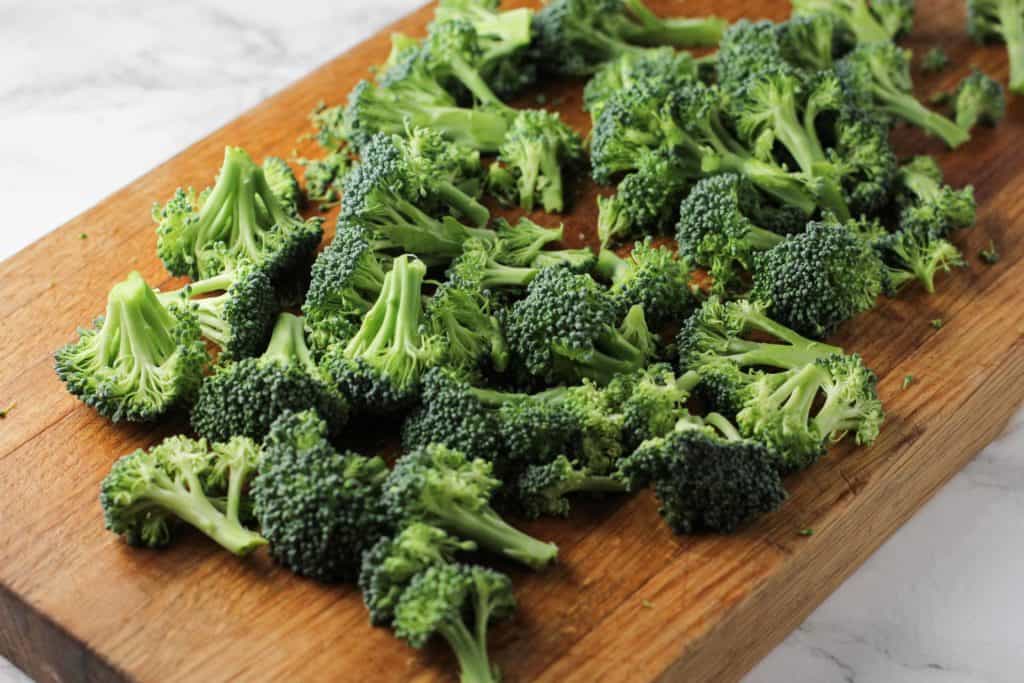 broccoli sitting on top of a wooden cutting board