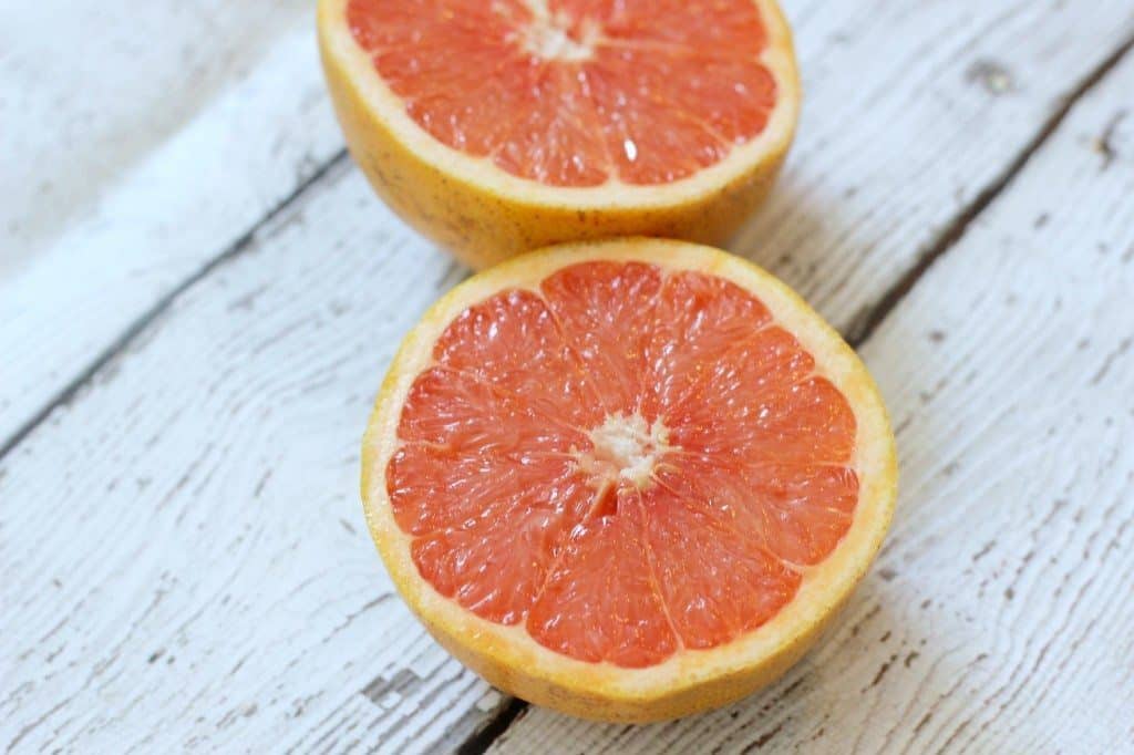 A close up of a sliced grapefruit on a wooden surface