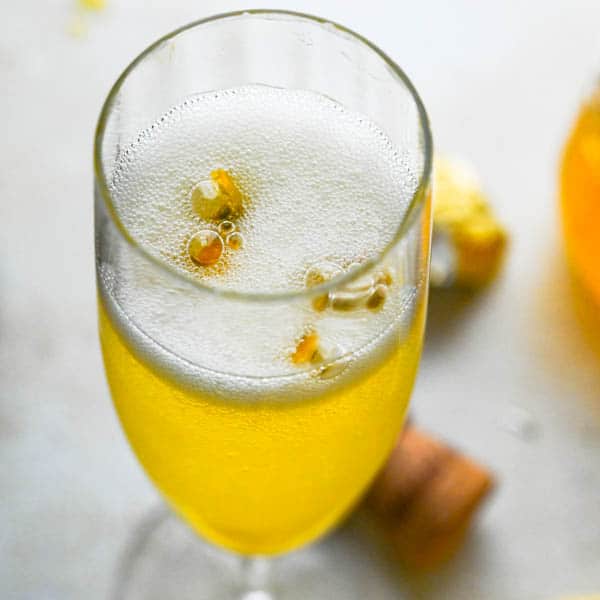 A close up of a glass of orange juice, with Fruit and Champagne
