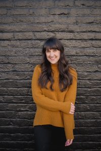 A woman standing in front of a brick wall