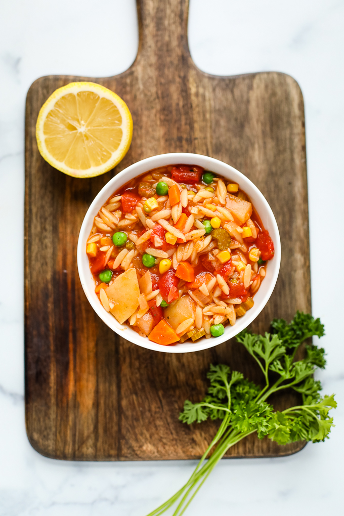 orzo vegetable soup in a bowl on a cutting board