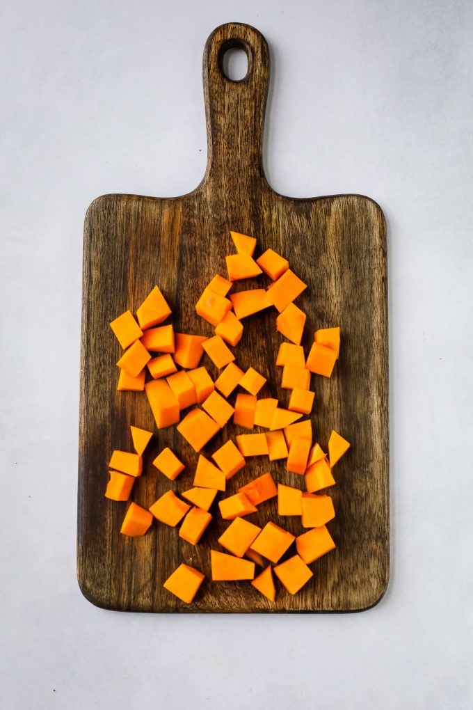 A wooden cutting board, with butternut squash on top